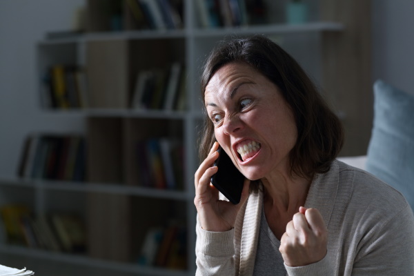 Angry adult woman calling on phone at night at home