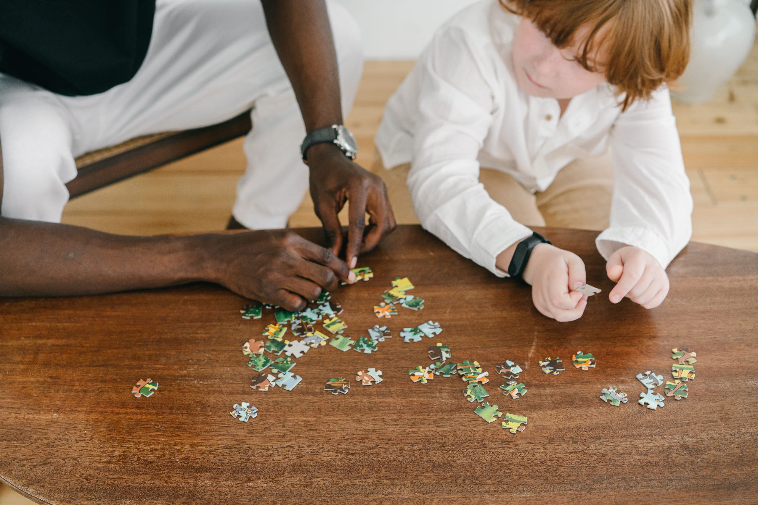 Ein Erwachsener und ein Kind puzzeln zusammen am Tisch